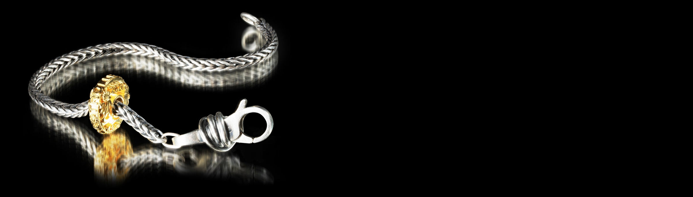 Silver bracelet with a gold-plated bead on a black background